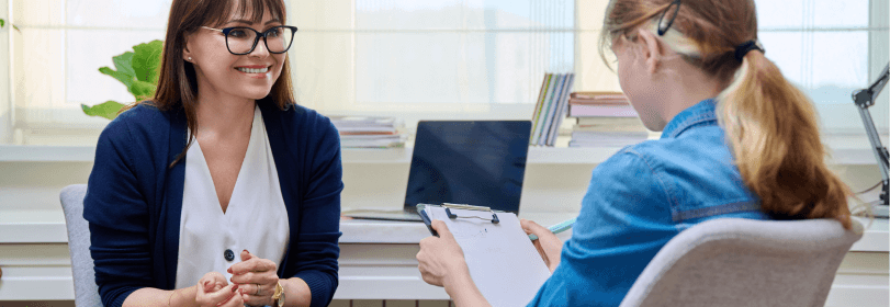 Image of a teacher helping a young person in a classroom